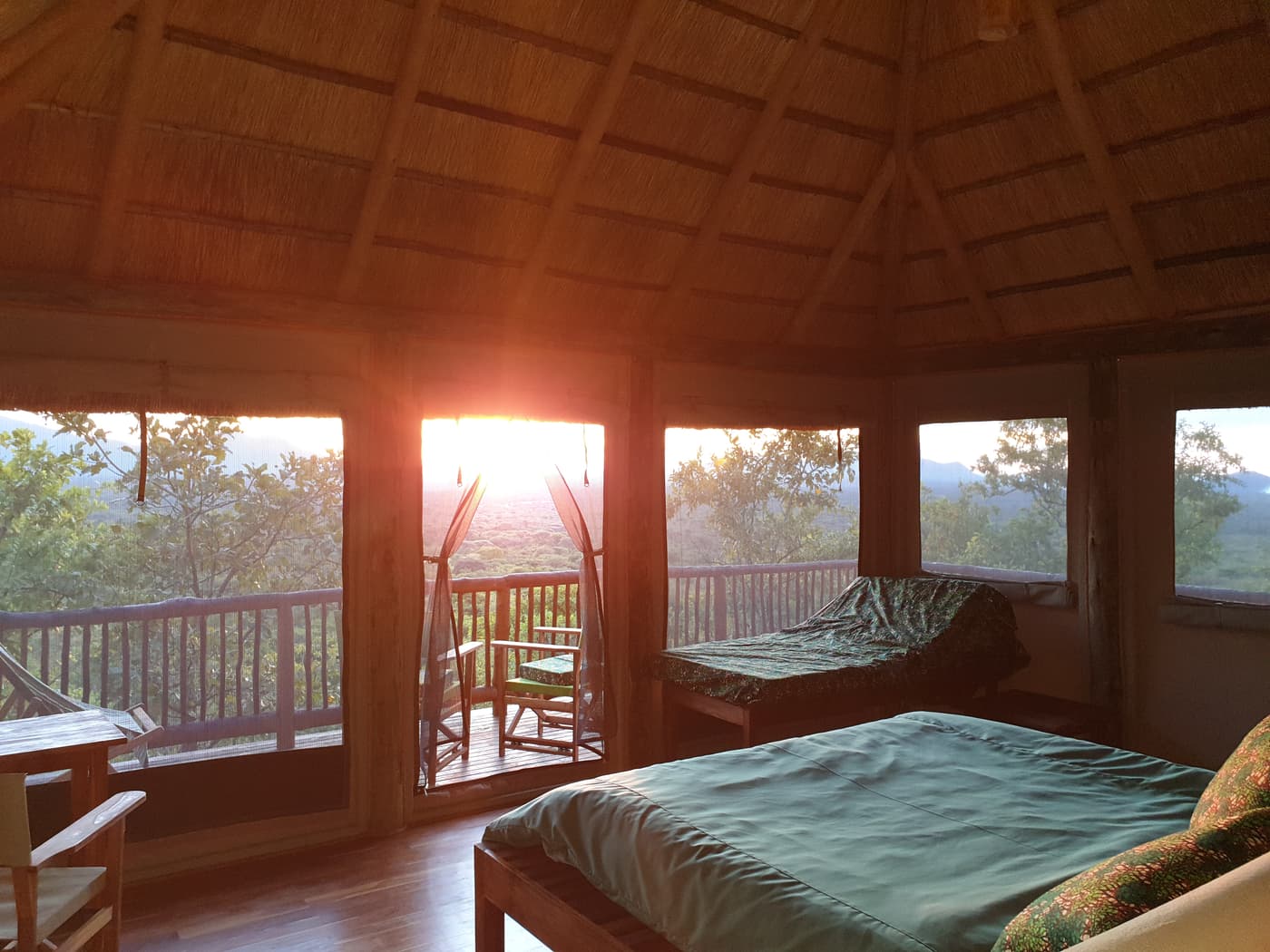 Thatched banda bedroom looking out to the sunset over the bush