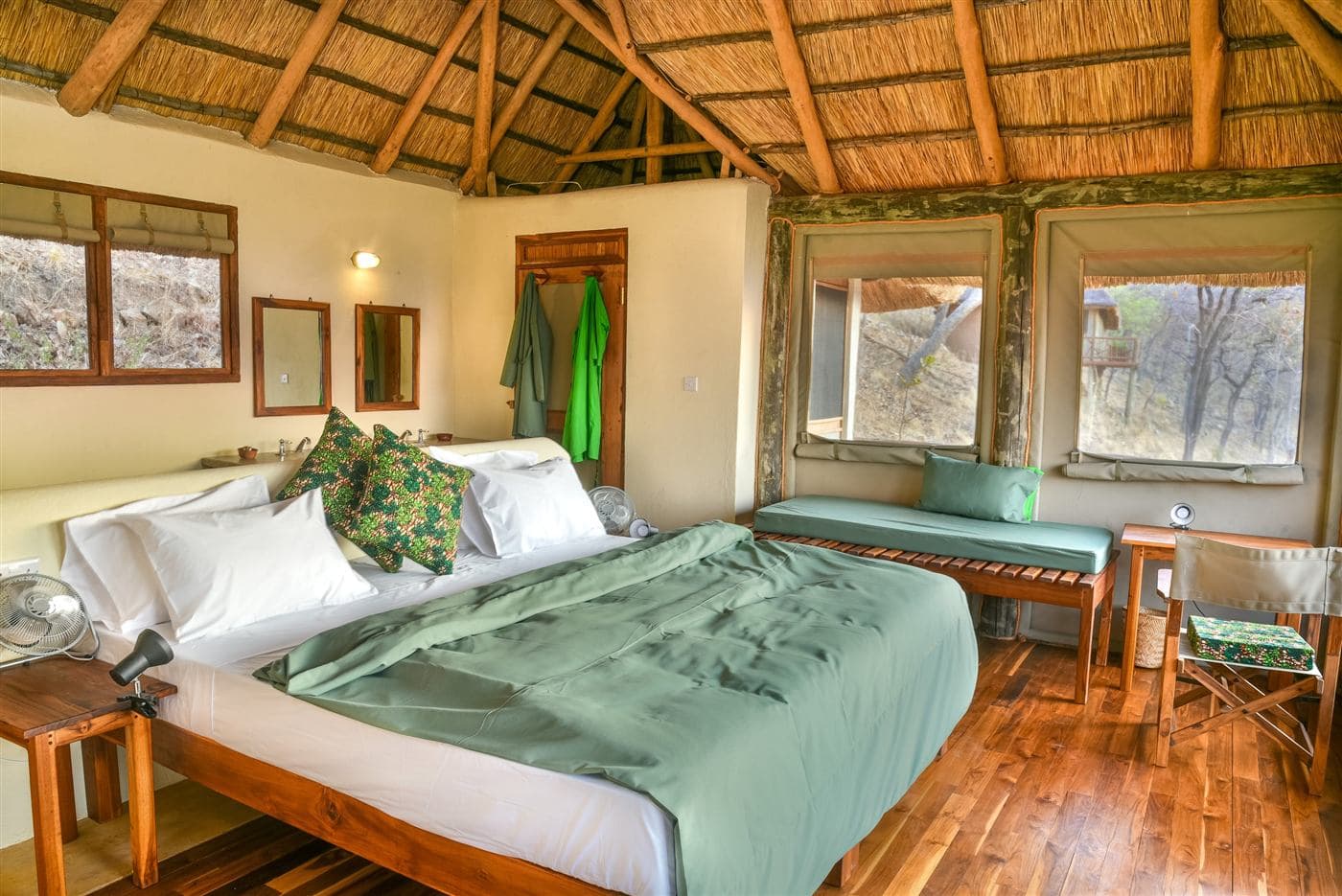 Bedroom in a thatched banda with green linen